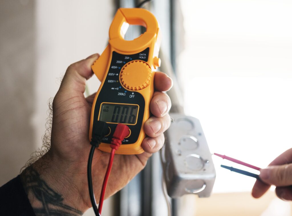 Electrician Holding a Digital Clamp Meter with Red and Black Test Leads