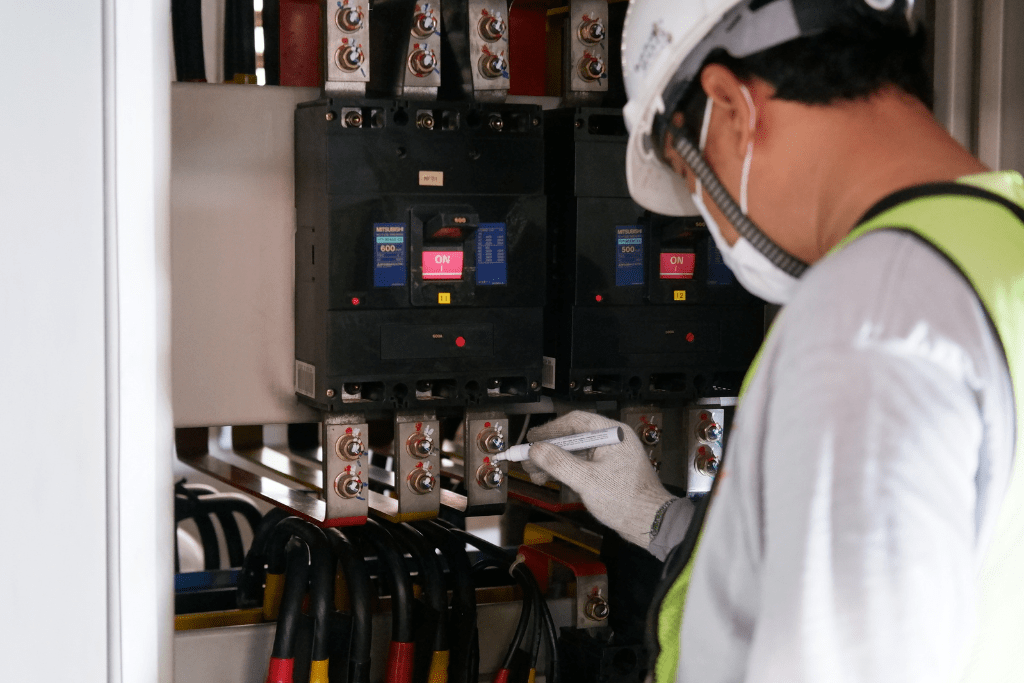 Electrician Inspecting Switchgear and Documenting Results During a Routine Maintenance Check