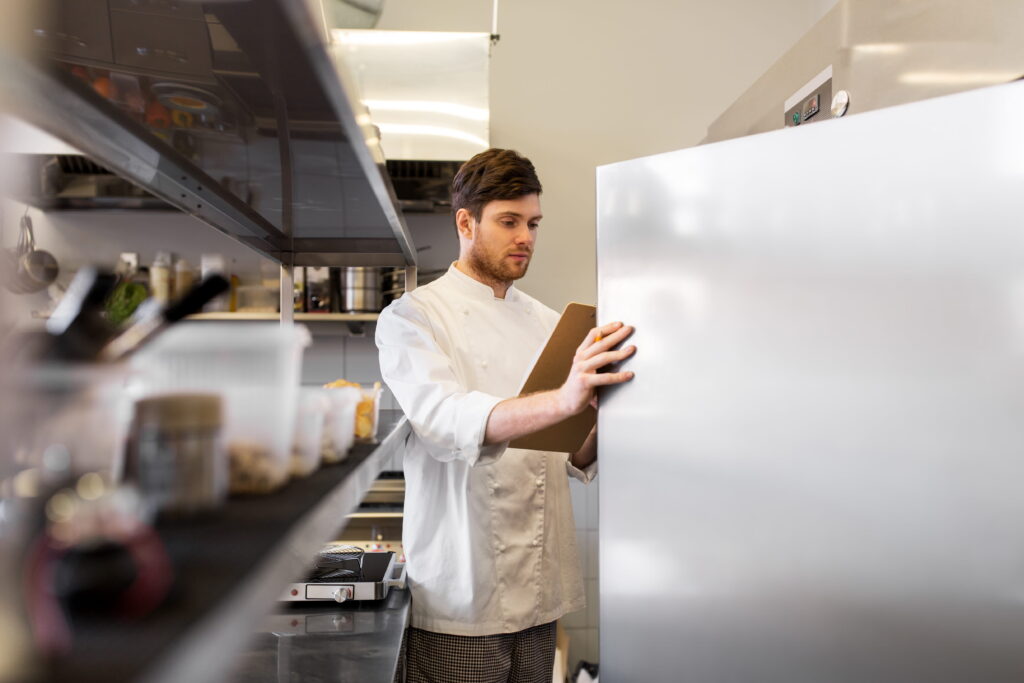 Chef Checking Temperature and Stock Inside a Commercial Kitchen Refrigerator