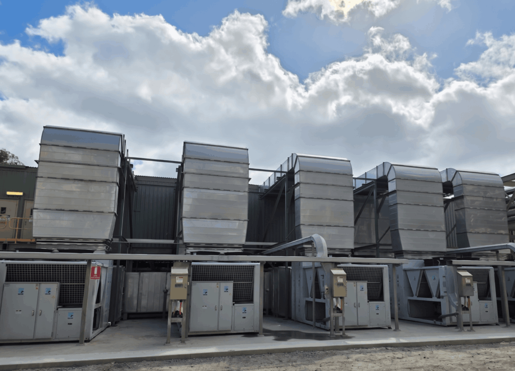 Five APAC package air conditioning units installed externally at a WA mining processing plant, with large insulated stainless steel ductwork rising above each unit